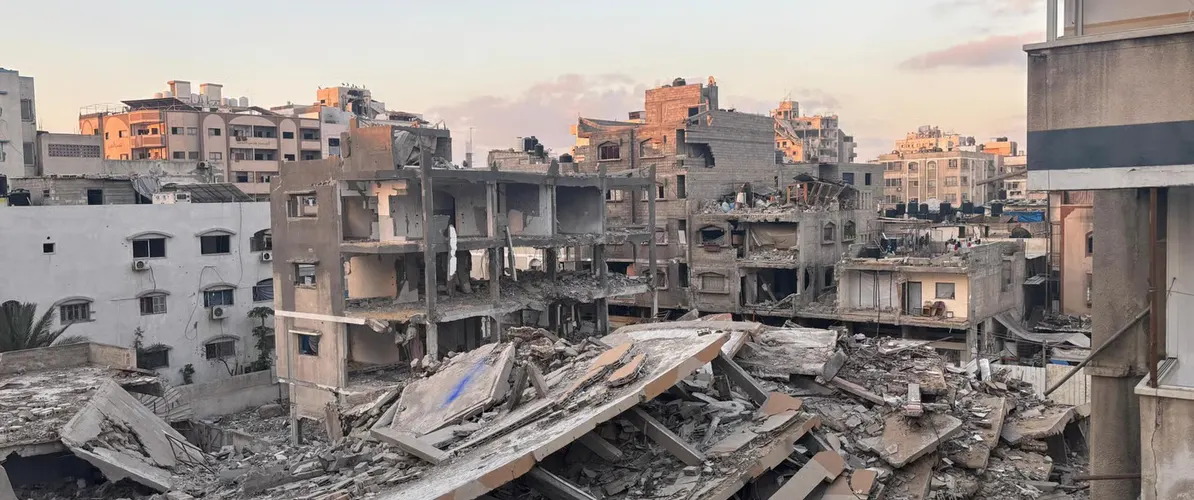 בניינים רבי קומות שקרסו וערימות הריסות בשכונה עירונית צפופה, באור דמדומים