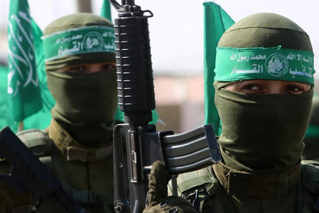 שני מחבלים רעולי פנים עם סרטי ראש ירוקים של גדודי עז א-דין אל-קסאם, רובה ודגלים ירוקים