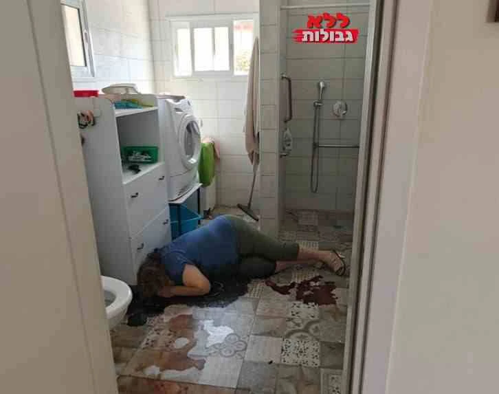 גופת אישה שרועה על רצפת חדר רחצה בבית מגורים, ליד מכונת כביסה, ודם על האריחים