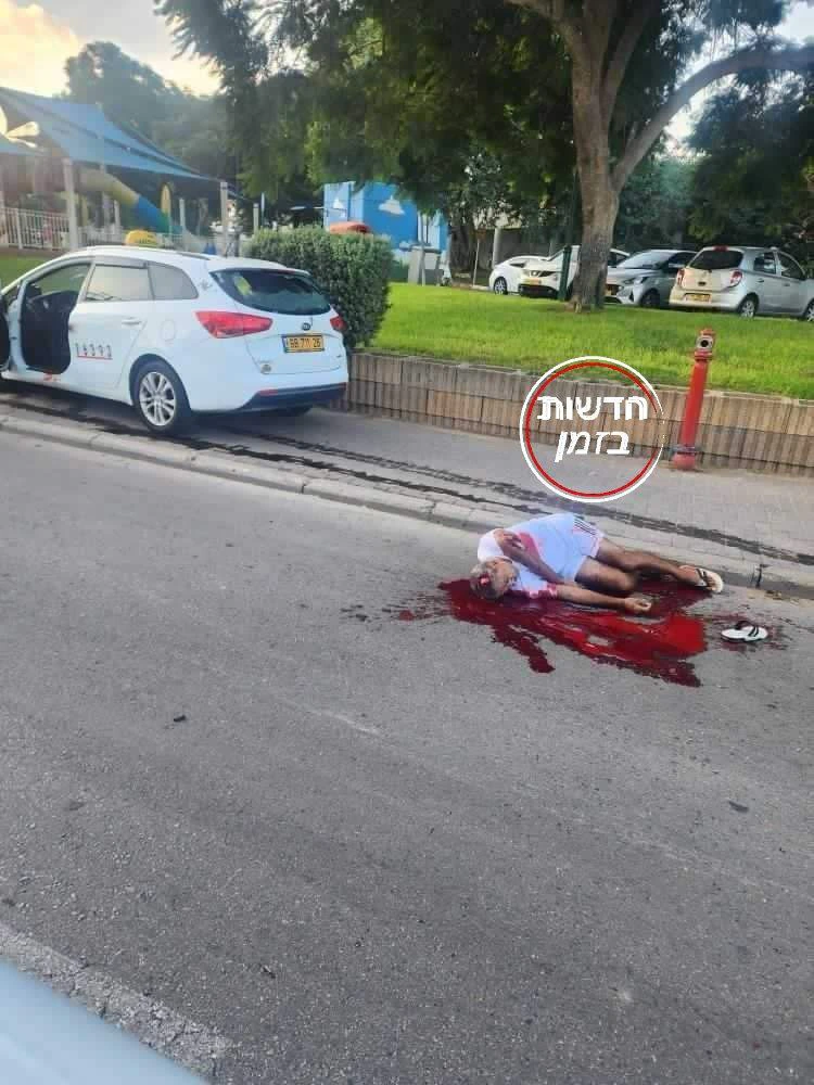 גופת גבר שרועה בשלולית דם על כביש עירוני, ליד מונית עם דלת פתוחה