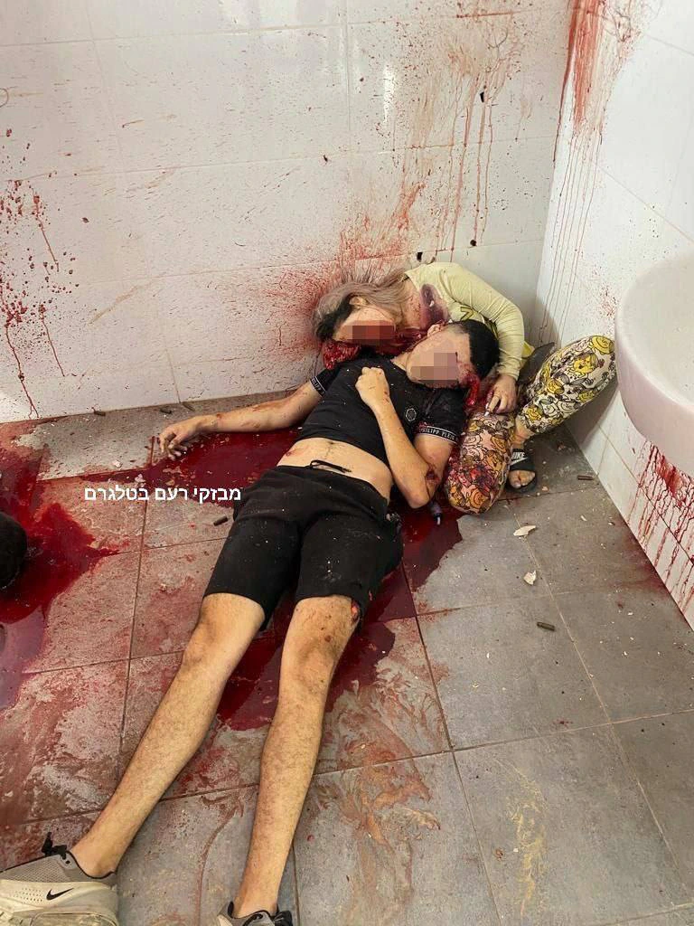 גופות צעיר וצעירה, פניהם מטושטשות, על רצפת חדר קטן מרוצף שקירותיו מוכתמים בדם