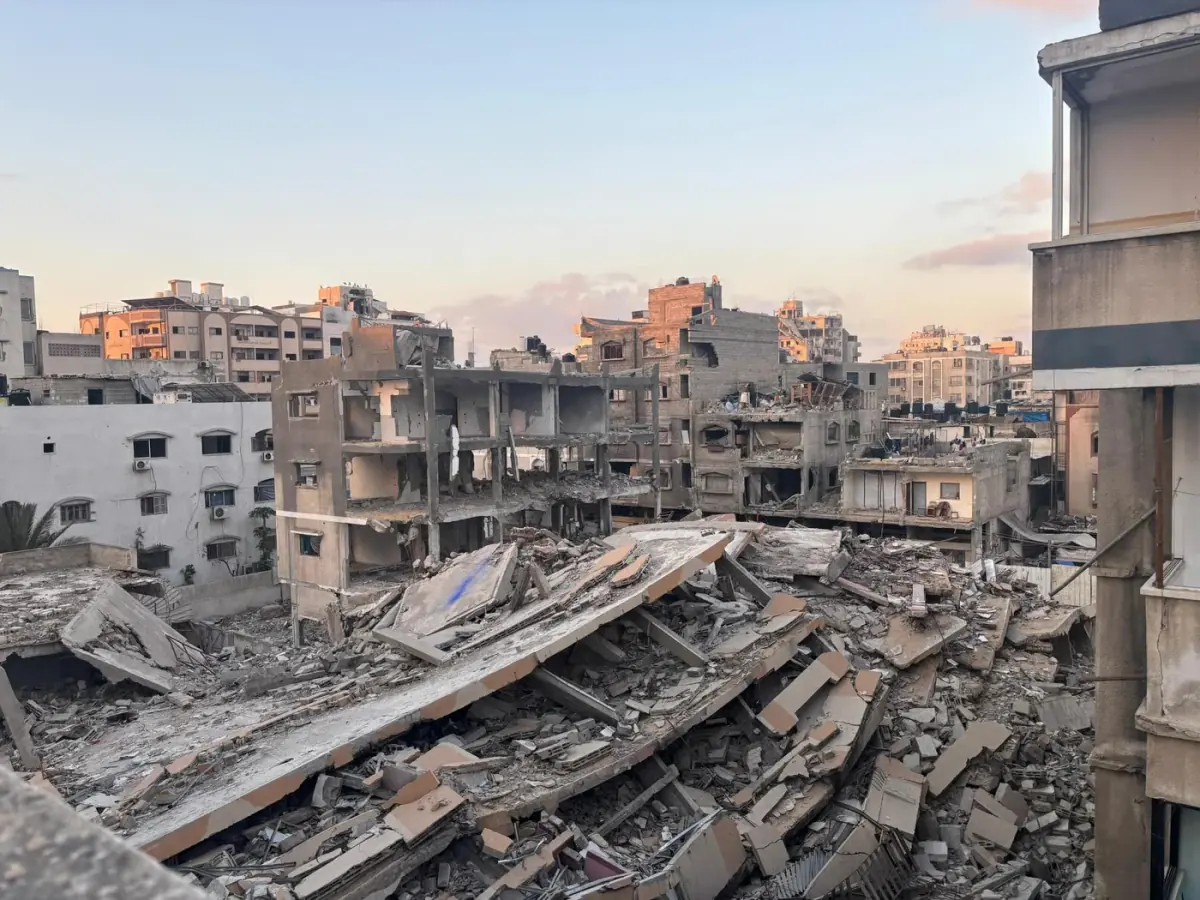 בניינים רבי קומות שקרסו וערימות הריסות בשכונה עירונית צפופה, באור דמדומים